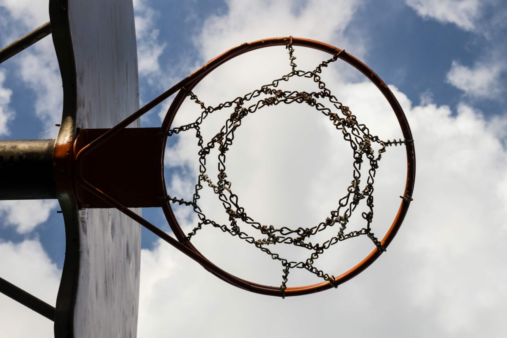 a shot of a basketball ring from below with the bright blue sky as the background