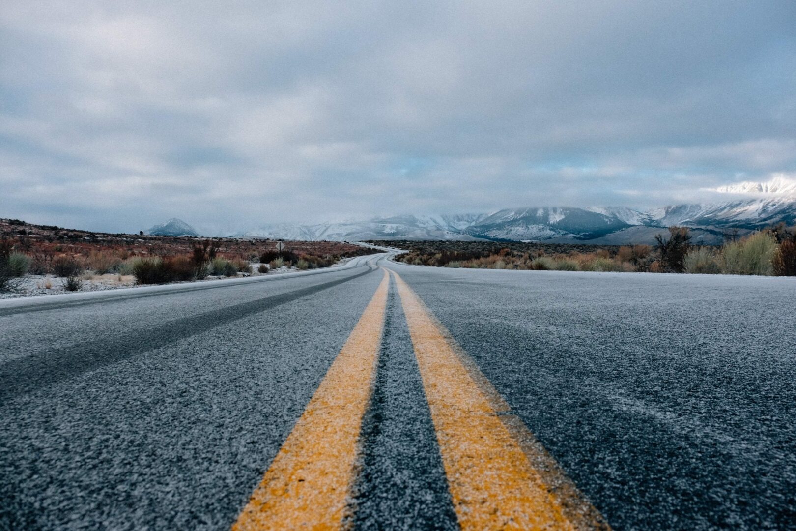 a close up shot of a road with yellow double line at the center with ice mountains at the far end