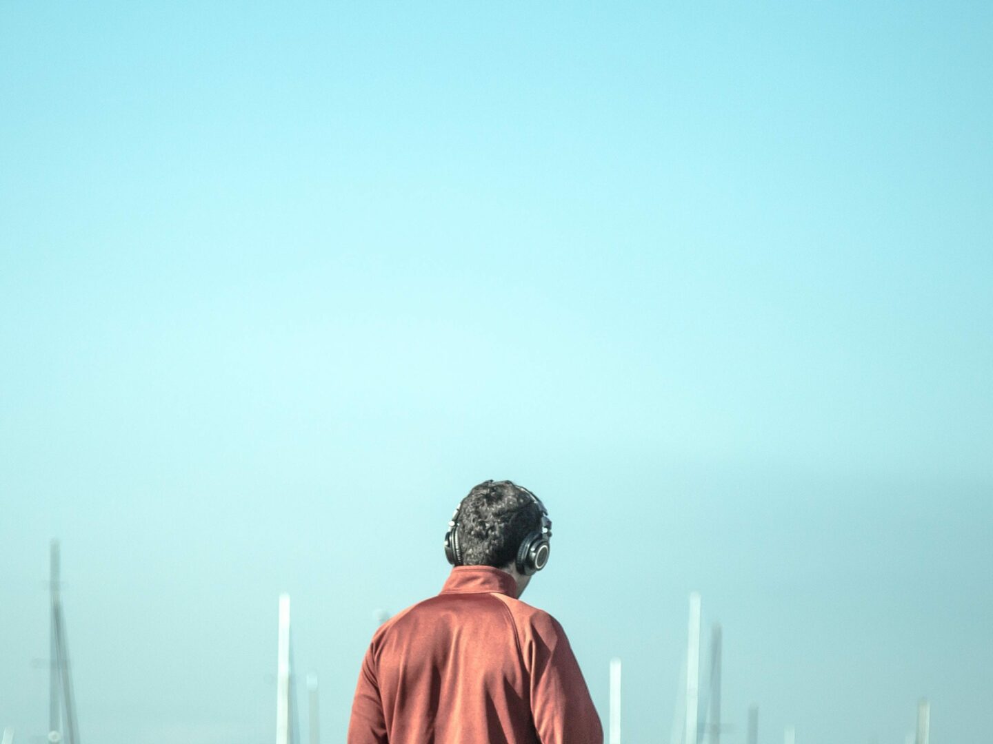 a shot of a man wearing a headphone with the background of an out of focus sky and tall buildings