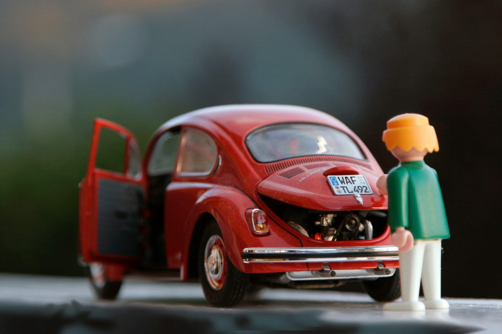 a shot of a red volkswagen beetle toy car with a human toy at the back of it