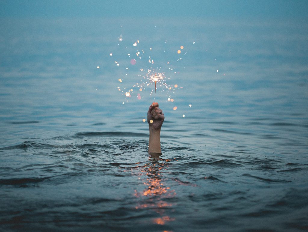 Hand Holding Sparkler in Water