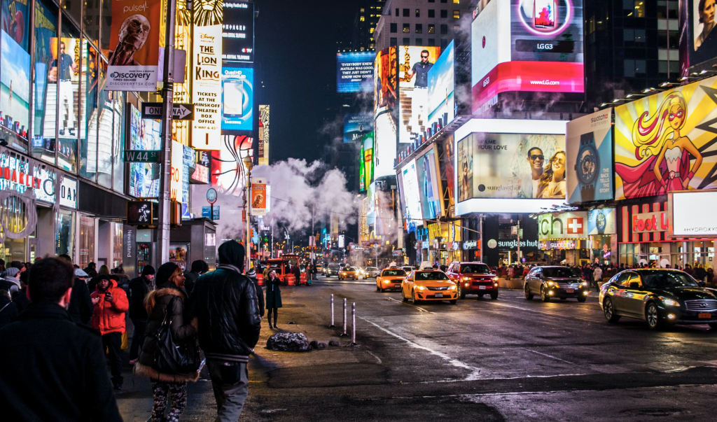 a shot of a busy road at night with cars on the road and billboards light up