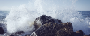 a photo of a stone being hit by the wave by the sea with the seawater splashing