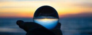 a shot of a hand holding a glass orb on the palm facing towards the horizon at dusk with the horizon inverted on the orb