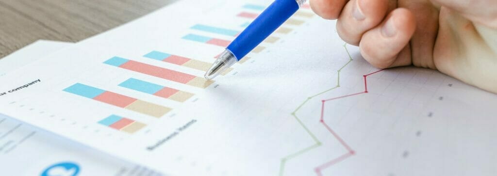 a close-up shot of a hand holding a pen pointing at a chart on a paper on a table